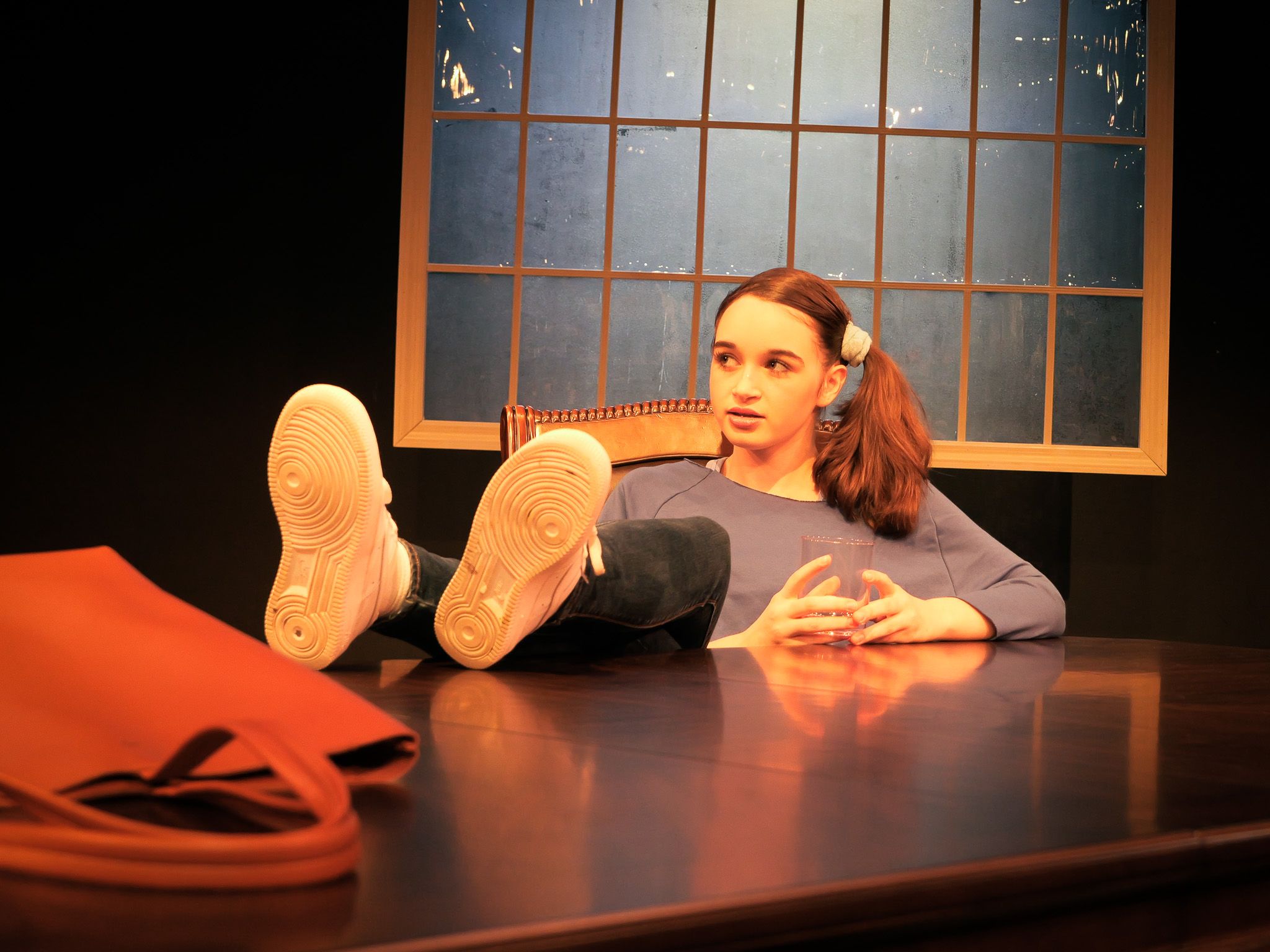 An actor sitting on a chair, legs crossed on a table